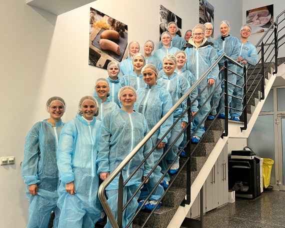 In Schutzkleidung gehüllte Schülerinnen und Schüler im Fleischverarbeitungsbetrieb Landhof